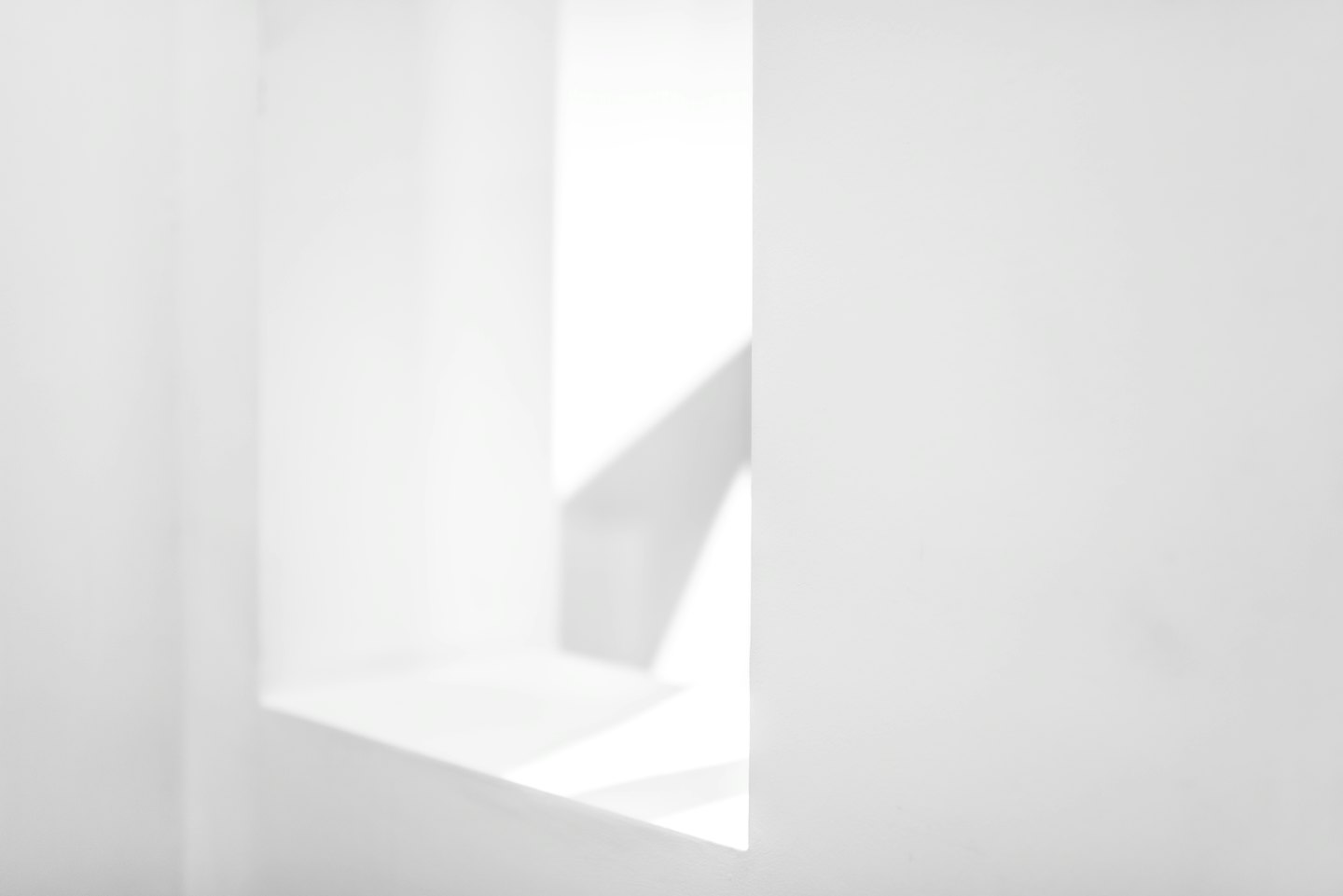 Białe geometryczne powierzchnie tworzące abstrakcyjne kształty architektoniczne.